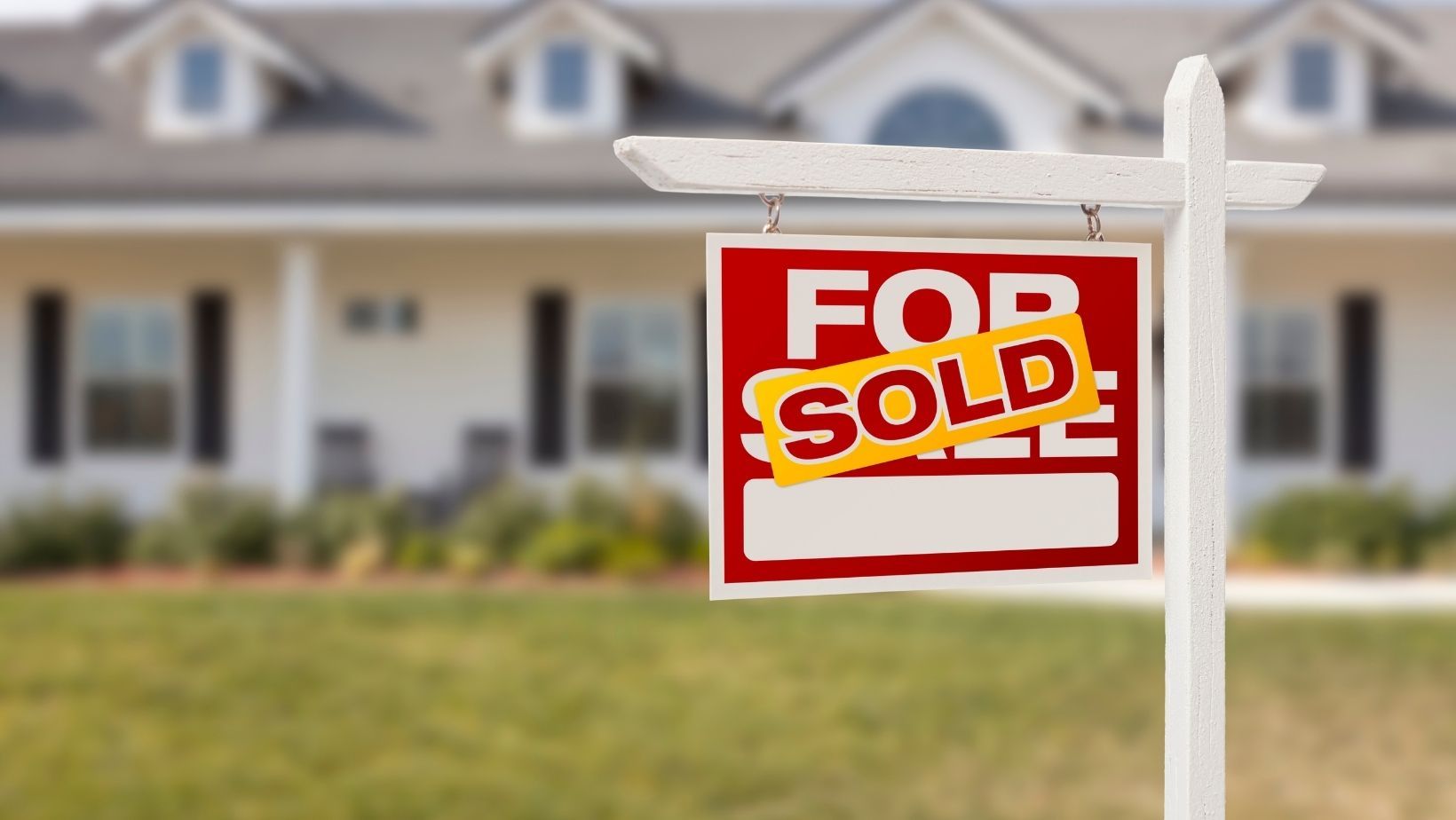 A For Sale Sign outside the house with a Sold Sticker on it.