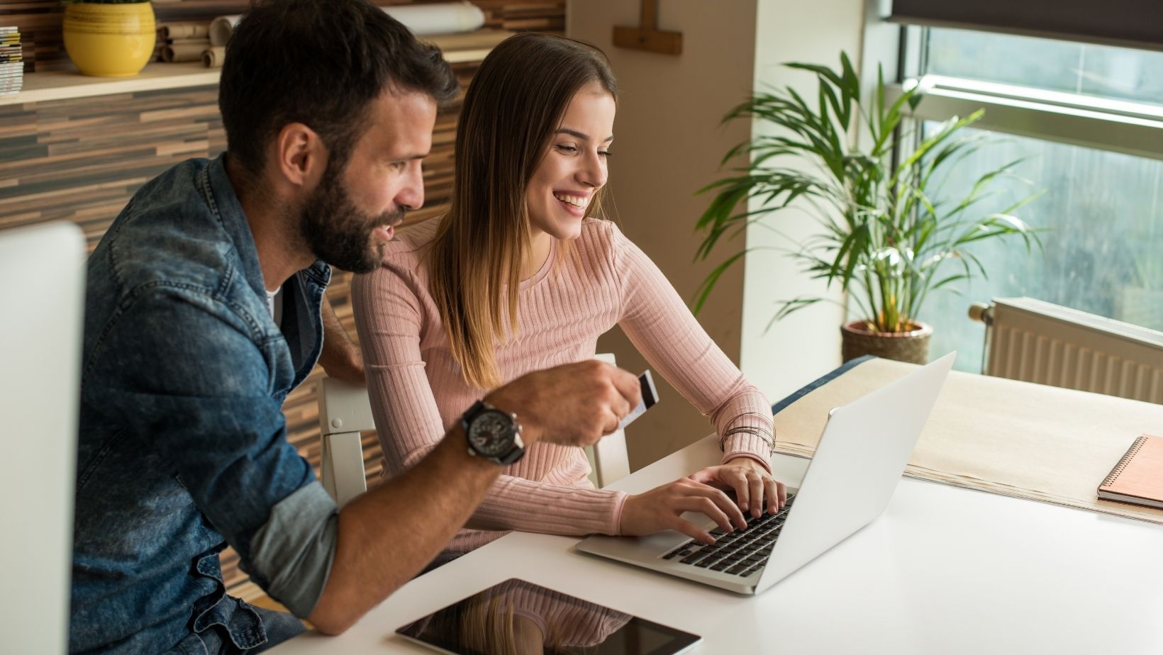 A young couple looking at a virtual tour of a home on their laptop