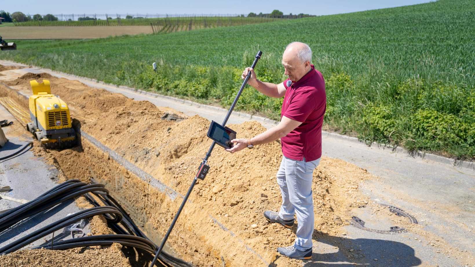 Man driving the total station into the trenches of the construction site.